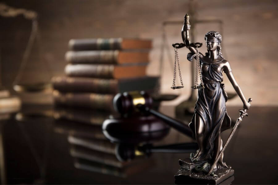 Figurka Temidy i&nbsp;młotek sędziowski na stole